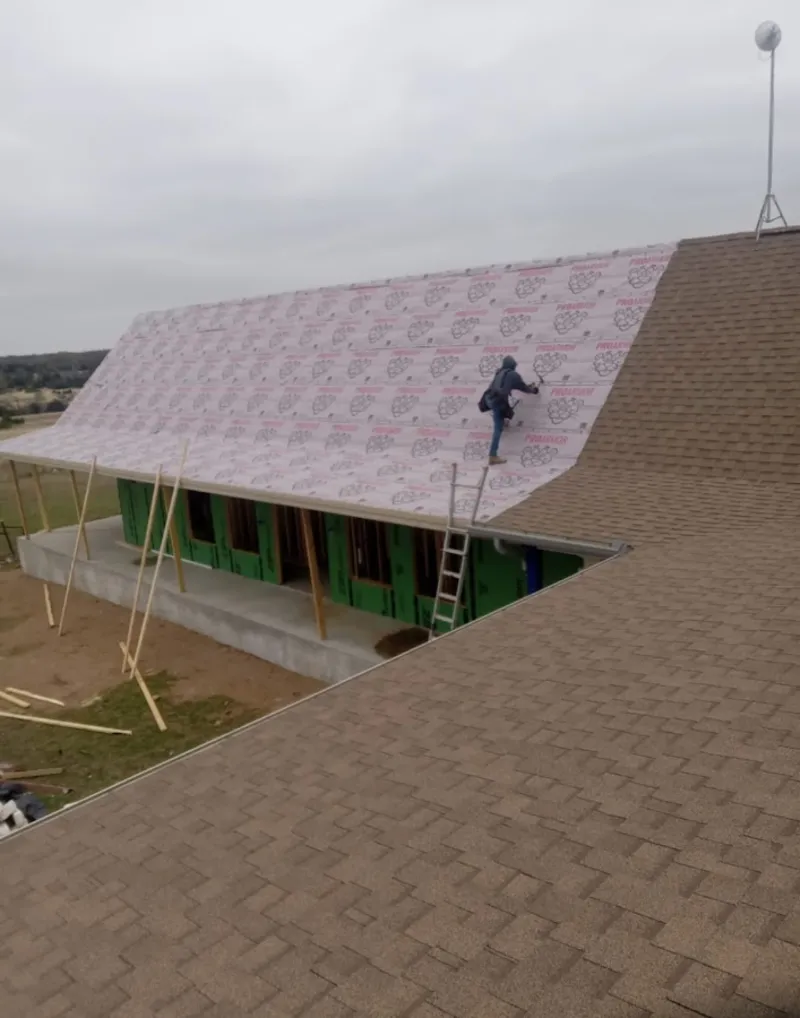 Worker preparing underlayment for a metal roof installation in Bellview
